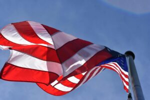 Close-up of a waving American flag under clear blue skies, symbolizing freedom and patriotism.